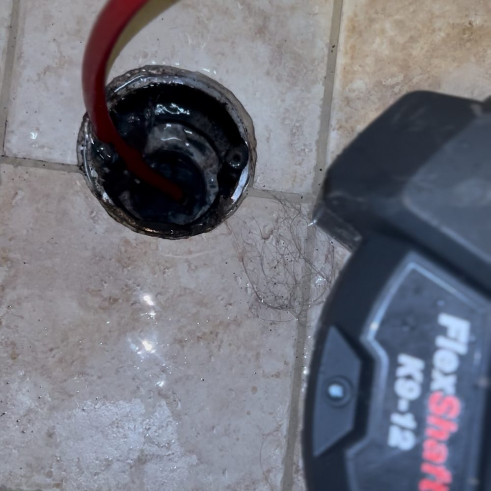 Water Wizard FlexShaft K9-12 descaling machine clearing grease, soap scum, and rust scale from a shower drain